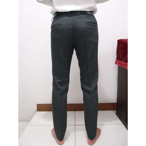 a man stands barefoot in a white shirt and black pants.