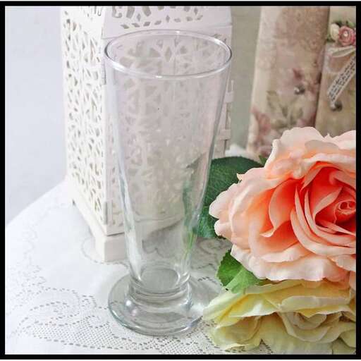 a glass vase with a pink rose next to a vase.