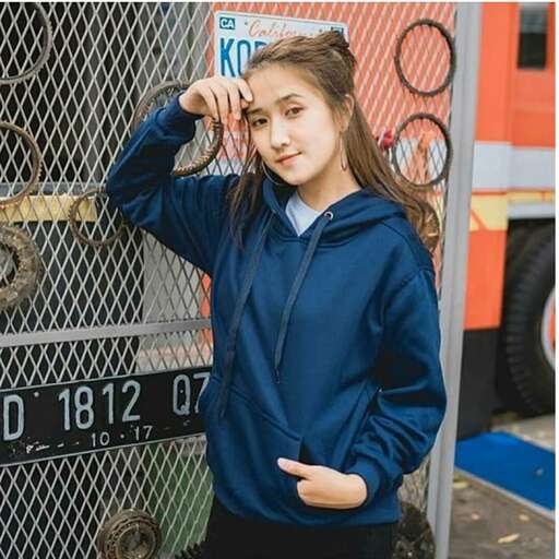 a girl in a blue hoodie stands in front of a fire truck.