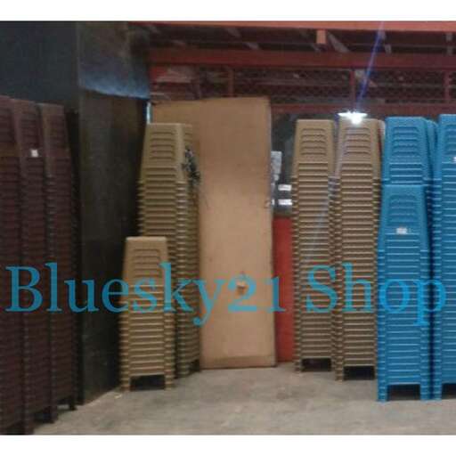a large stack of blue plastic chairs in a warehouse.