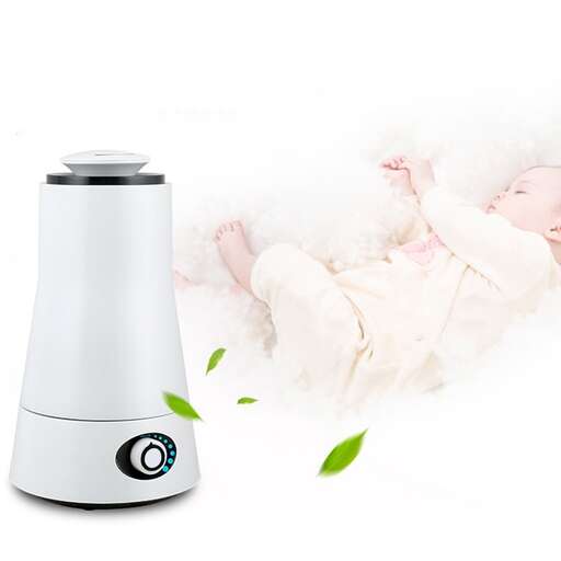 a baby in a blanket with a small appliance.