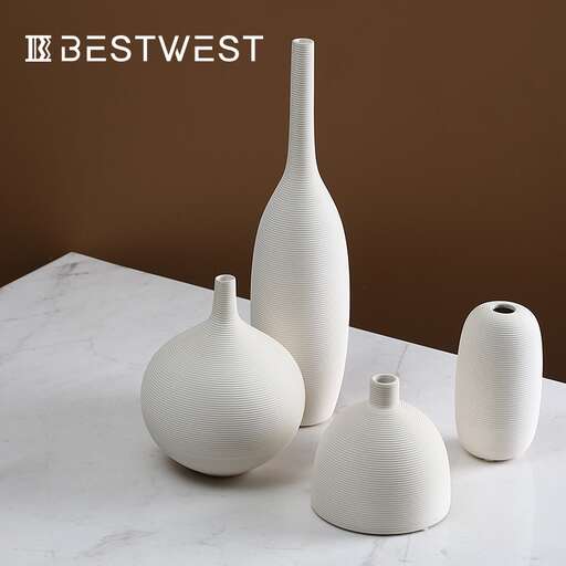 a white vase and two smaller vases on a table.