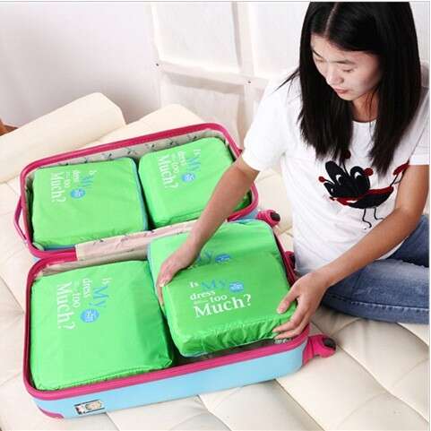 a woman sitting on a couch holding a suitcase filled with green and white cloths.