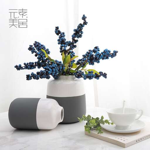 a vase with blue flowers and a white bowl on a table.