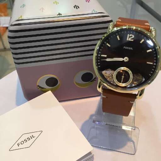a watch on a table with a piece of paper.