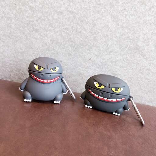 two cute little monsters sitting on a bench in a park.