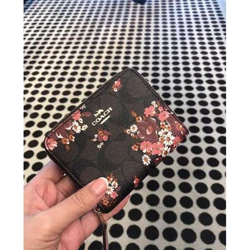 a hand holding a small purse with flowers on it.