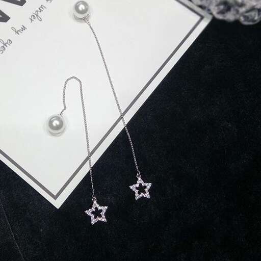 a pair of earrings with a small star on a chain.