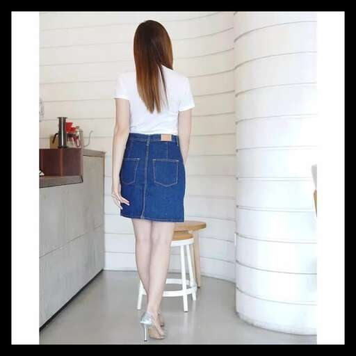 a woman in a denim skirt stands on a stool.