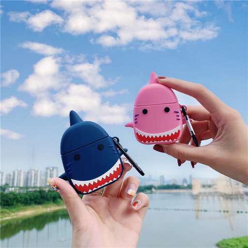 a pair of hands holding a toy that looks like a shark.