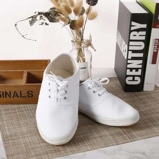 a pair of white shoes with a flower in the vase
