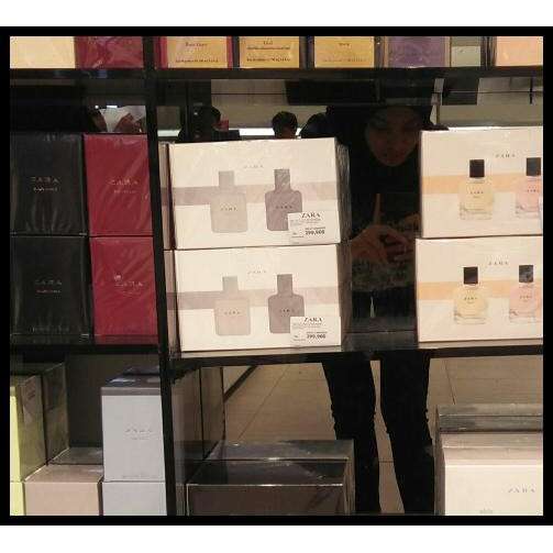 a woman looking at books in a glass case.