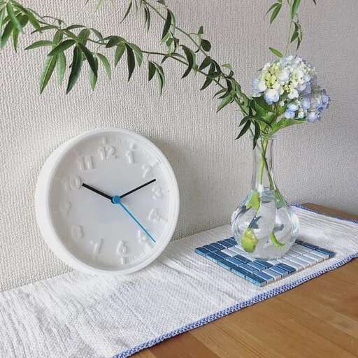 a white clock sitting on top of a white rug.