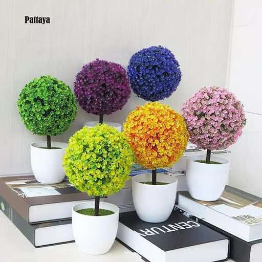 a collection of colorful trees in white pots.