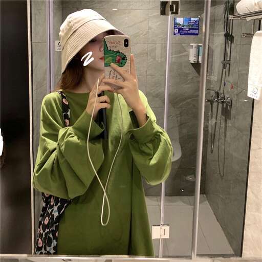 a girl in a green jacket taking a selfie in a mirror.