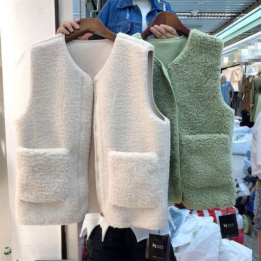 a man shows off a large white towel with green and white vests.