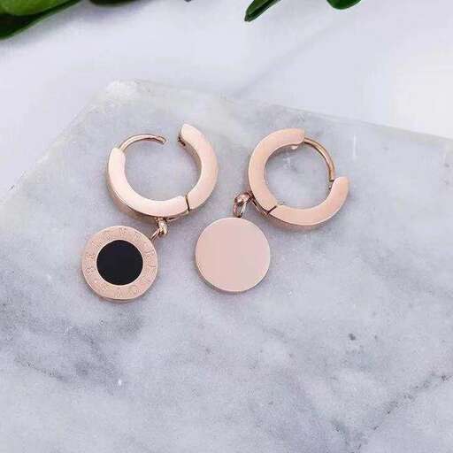 a pair of gold hoop earrings with a black round top.