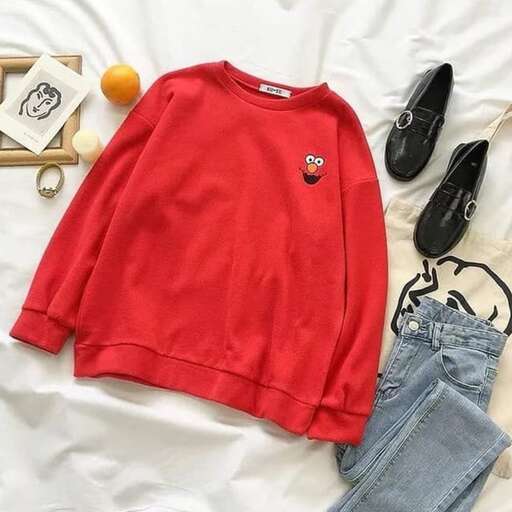 a red sweater with a pair of jeans and shoes on a white sheet.