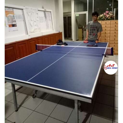 a man standing next to a table with a ping pong table