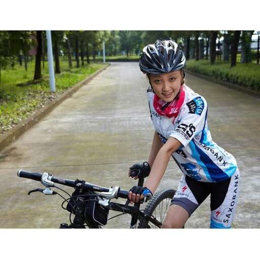 a young girl riding a bike down a road.