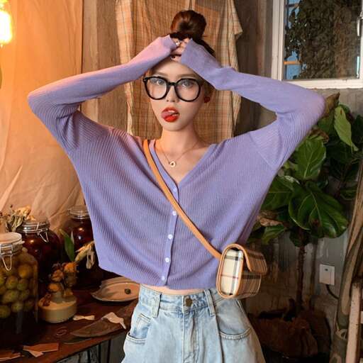 a model wearing a long sleeved shirt and denim skirt.