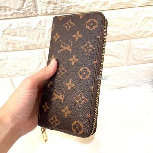 a hand holding a wallet with a picture of a ship on it.