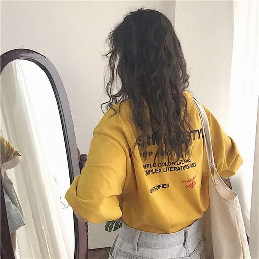 a woman in yellow shirt looking in mirror