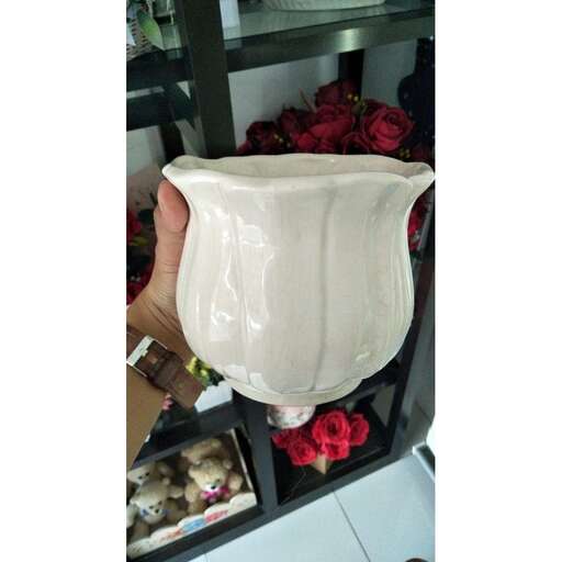 a white vase is being held up by a person.