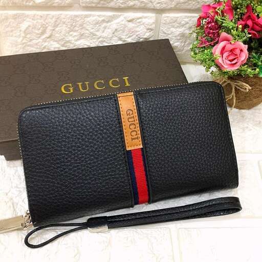 a black leather bag with a gold strap and a pink flower.