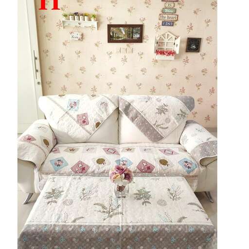 a couch with a flowered pillow and a flower vase.