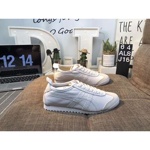 a pair of white shoes sitting on a couch next to a laptop.