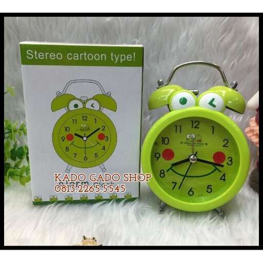 a green alarm clock with a cartoon face and a clock.