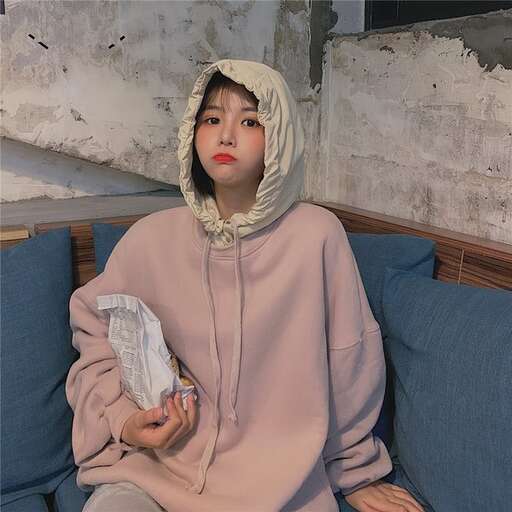 a woman in a hoodie sitting on a blue couch.