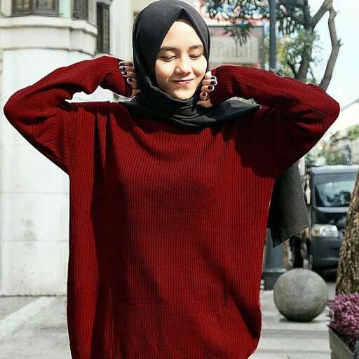 a woman wearing a red sweater with a black scarf around her neck