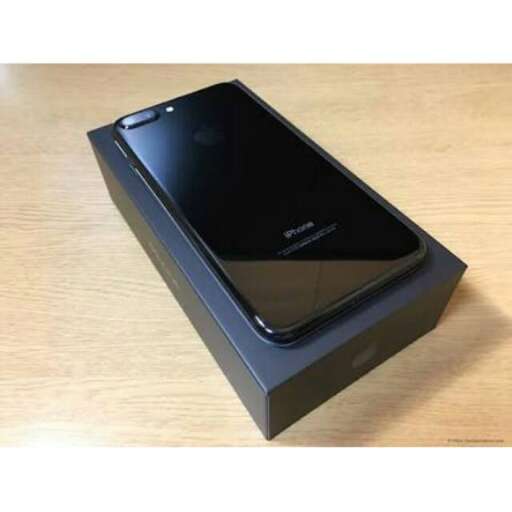 a black cell phone sitting on a wooden table.
