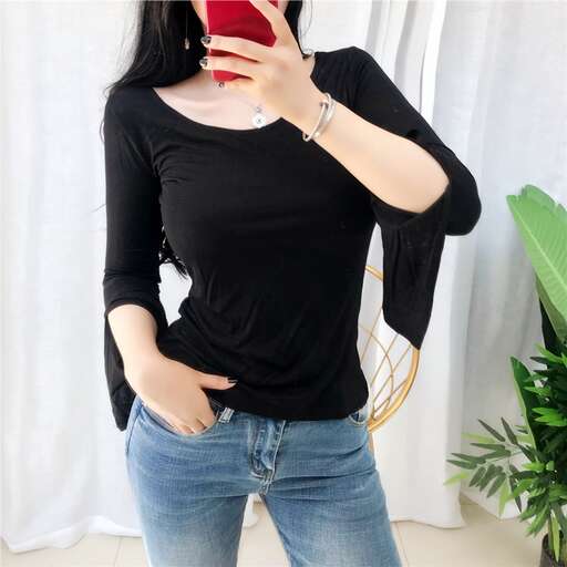 a woman in a black top and jeans holding a red cell phone.