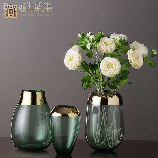 a large green vase with a gold vase with white roses.