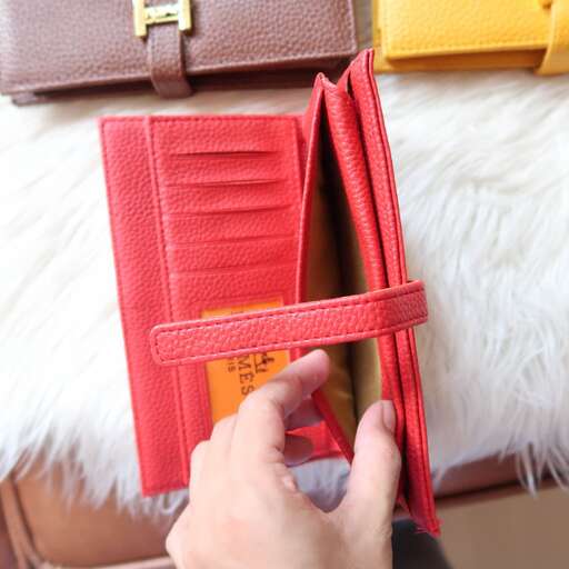 a hand is opening a wallet with a zipper.
