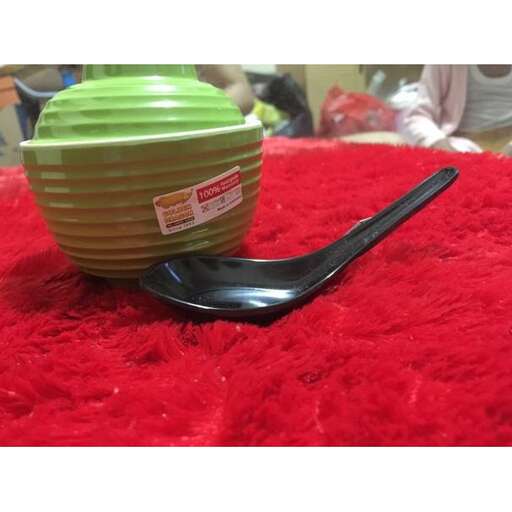 a spoon sitting on a red blanket next to a cup.