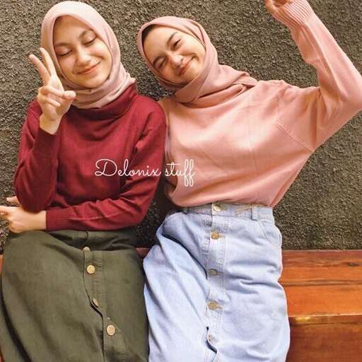 two young women sitting on a bench with their hands up.