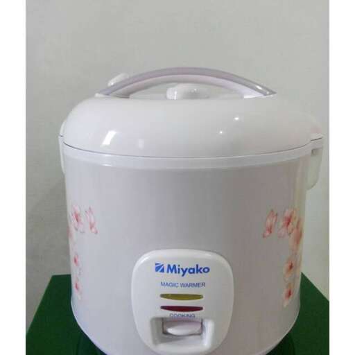 a white crock pot with a handle on a green table.