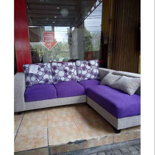 a purple couch sitting on a sidewalk next to a window.
