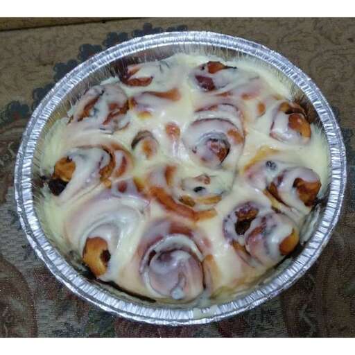 a dish of cinnamon and cinnamon rolls covered in icing.