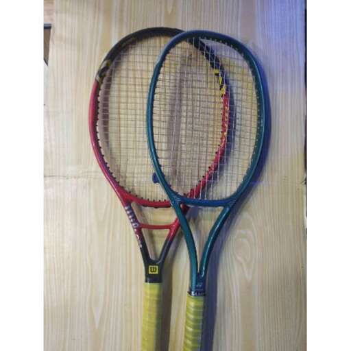 two tennis rackets are shown on a wooden surface.