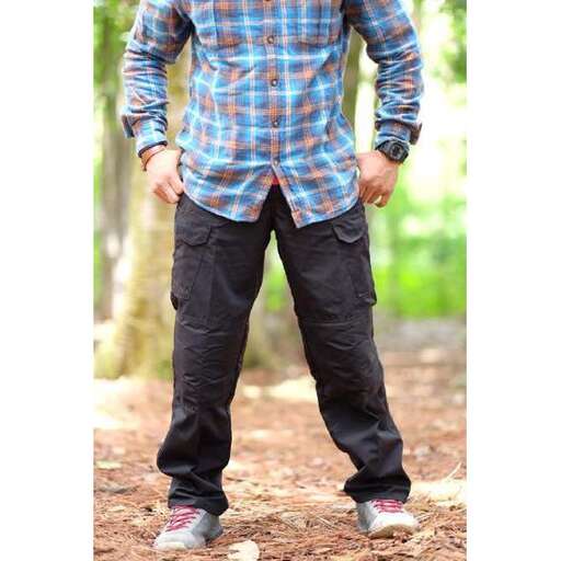 a man in a plaid shirt stands in the forest.