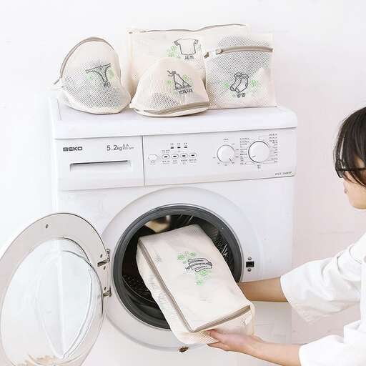 a woman putting a towel into a washing machine.