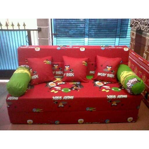 a red couch with green pillows on it.