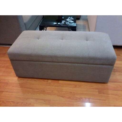a small gray ottoman sitting on a wooden floor.