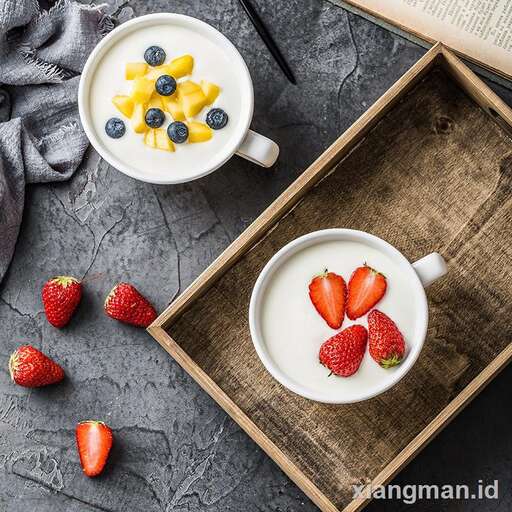 a cup of yogurt with strawberries and a book.