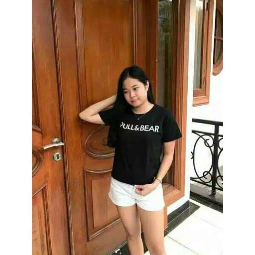a girl in shorts and a t - shirt is standing in front of a door.